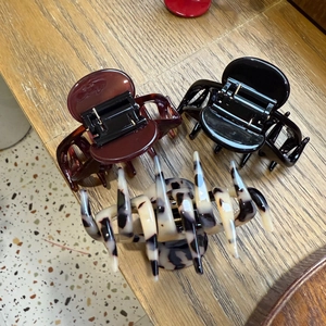 Détail de trois pinces à cheveux en acétate : rouge foncé, noir uni et motif écaille de tortue