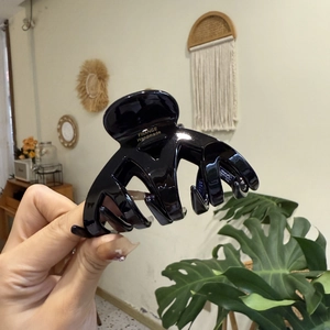 Gros plan d'une pince à cheveux en acétate noir avec logo France Handmade doré