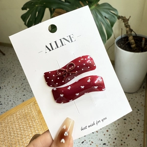 Polka dot wavy hair clip set with brown bows on a display card held by hand