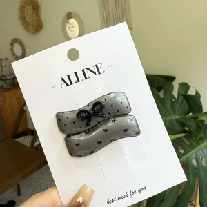 Polka dot wavy hair clips set with black bows on a white card against a cozy background