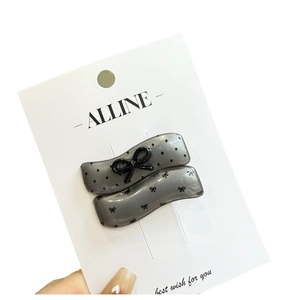 Polka dot wavy hair clip in smoky gray with delicate black bow knot on display card