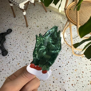 Detail view of acetate shark hair claw with green marble texture and red glitter accents