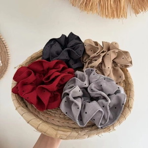 Detail of four colorful polka dot scrunchies in a woven tray with a clean boho vibe