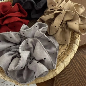 Detailed macro view of four elegant polka dot hair scrunchies in a woven basket