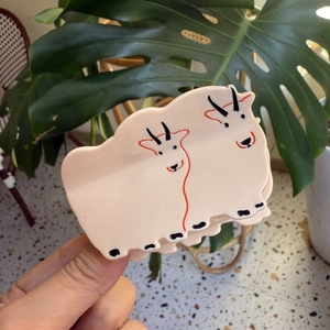 Gros plan détaillé d'une pince à cheveux en acétate crème avec motifs de chèvres mignons