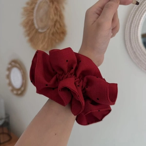 Deep red polka dot oversized fabric scrunchie worn on wrist for an elegant hair look