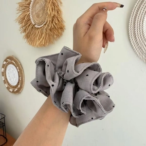Elegant oversized grey polka dot scrunchie made of layered fabric worn on the wrist