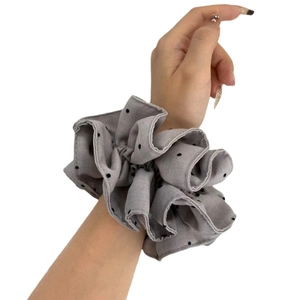 Elegant grey polka dot fabric scrunchie with oversized ruffles worn on a model's wrist