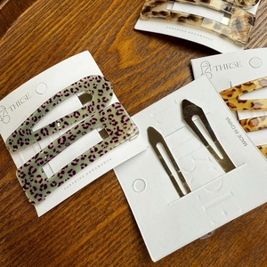 Detail of leopard print acrylic hair clips and metal slides on a wooden surface