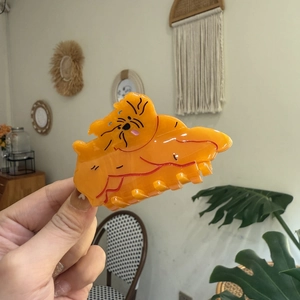 Gros plan d'une pince à cheveux orange en acétate en forme de chien Corgi mignon et brillant
