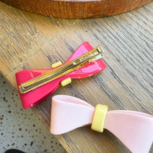 Detail of rose and pink bow hair clips with Korea engraving on gold metal duckbill base