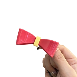 Pink and yellow bow-shaped resin hair clip with glossy finish for women