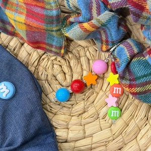 Detailed macro shot of British plaid scrunchie with colorful M-letter beads and star charm