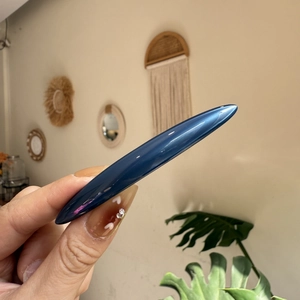 Détail d'une barrette à ressort en acétate bleu marine tenue à la main à domicile