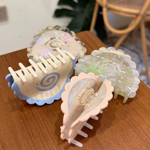 Close-up of pastel spiral hair claws with shell luster on a wooden background