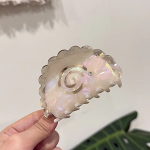 Close-up of cream marble claw clip with swirl pattern and sparkling rhinestone detail
