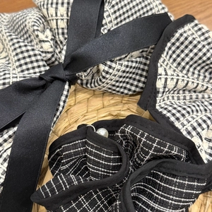 Détail d'un chouchou à carreaux français avec nœud en satin noir et perle élégante