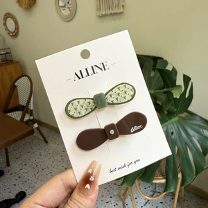 Floral print and brown glossy bow hair clips set on a display card in a warm home setting