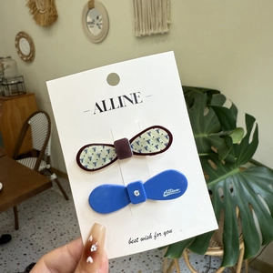 Polka dot bow and blue rhinestone duckbill hair clips set on a display card