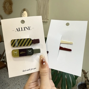 Close-up of preppy plaid and lettered hair clips set on a display card for styling
