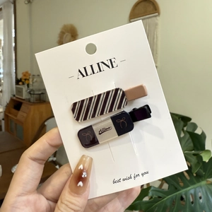 Set of minimalist plaid and bow duckbill hair clips on white card held in hand