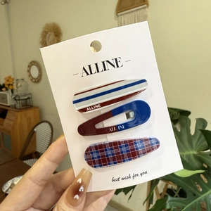Close-up of three checkered and striped plaid hair clips on a white display card