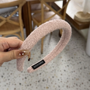 Détail du tissu peluche rose et de l'étiquette faite main sur ce serre-tête rembourré épais