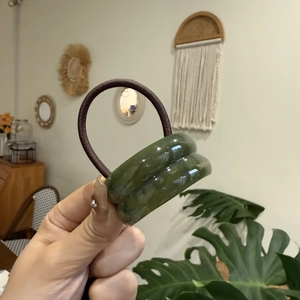 Detailed macro view of dark green resin oval rings and brown elastic hair tie