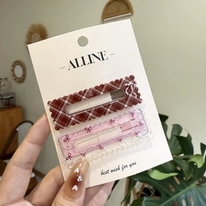 Détail de barrettes à carreaux rouges et nœuds roses sur carte de présentation