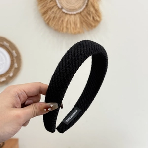 Detail shot of black knitted headband featuring handmade label and textured ribbed fabric