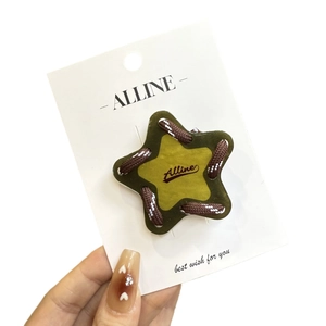 Pince à cheveux étoile tressée en vert olive et jaune sur carte de présentation