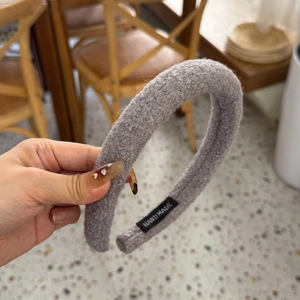 Détail du serre-tête rembourré en polaire grise avec texture épaisse et étiquette handmade
