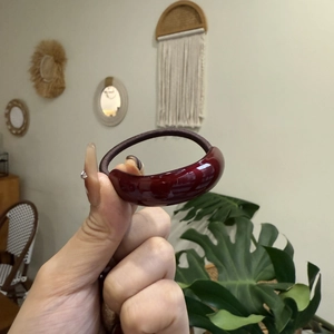 Detail view of a wine red resin hair tie with a glossy finish and elastic band