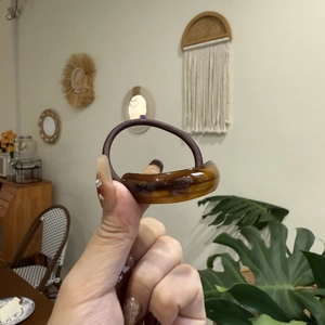 Detailed shot of amber resin hair tie with gold Sunshine lettering and brown elastic