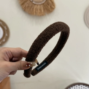 Détail d'un serre-tête en peluche marron avec étiquette faite main et texture
