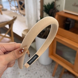 Detail of a thick cream sponge headband with handmade label and soft knit texture