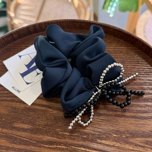 Detailed view of navy blue silk hair tie featuring a beaded bow and ruffled fabric