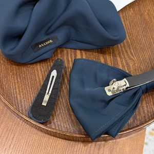 Detailed view of dark blue silk-textured bow hair clip with polished metal spring clasp