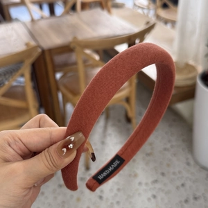 Detailed shot of handmade brick red sponge headband with fine knit texture and black woven label