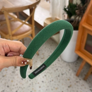 Close-up of a dark green sponge headband with knitted texture and handmade interior label