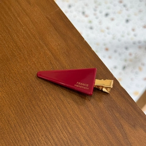 Detail of red triangle hair clip with golden France Handmade lettering and metal clip