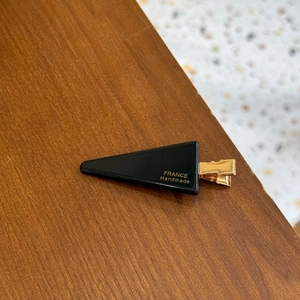 Detailed macro view of black triangle hair clip with golden metal base and France Handmade text