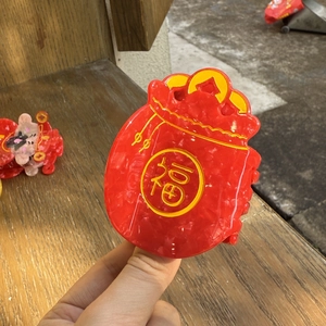 Detail van rode haarclip in de vorm van een gelukszakje met Fu-teken en marmeren textuur