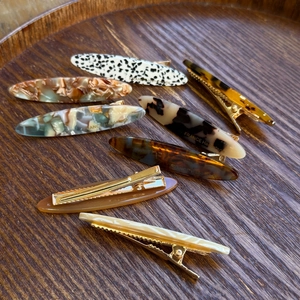 Détails d'élégantes barrettes en acétate avec gravure dorée et motifs variés chic