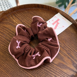 Vue détaillée du chouchou en velours côtelé avec broderie nœud rose et bordure rose