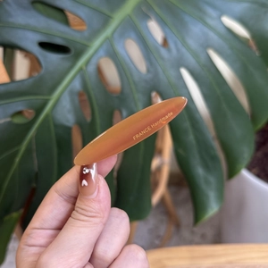 Barrette en acétate ambre élégante avec lettrage doré France Handmade sur fond de feuille