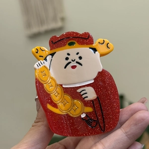 Detailopname van een schattig God van Rijkdom acryl accessoire met rode glitters