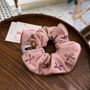 Détail du chouchou en velours rose avec motifs de nœuds et bouton décoratif mode