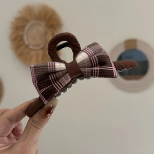 Détail de la pince à cheveux marron en tissu avec un nœud papillon à carreaux rose