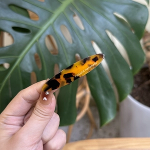 Détail d'une barrette en acétate écaille de tortue avec logo doré et petits cristaux